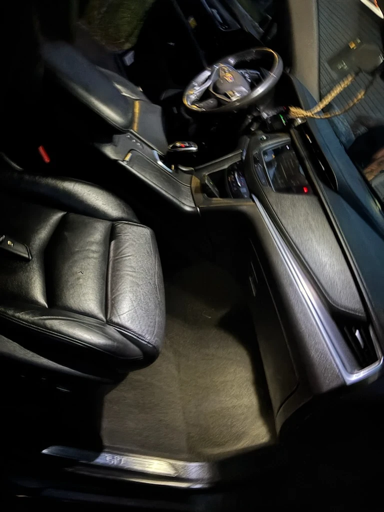 Cadillac front passenger area with vacuumed carpet and conditioned black leather seat
