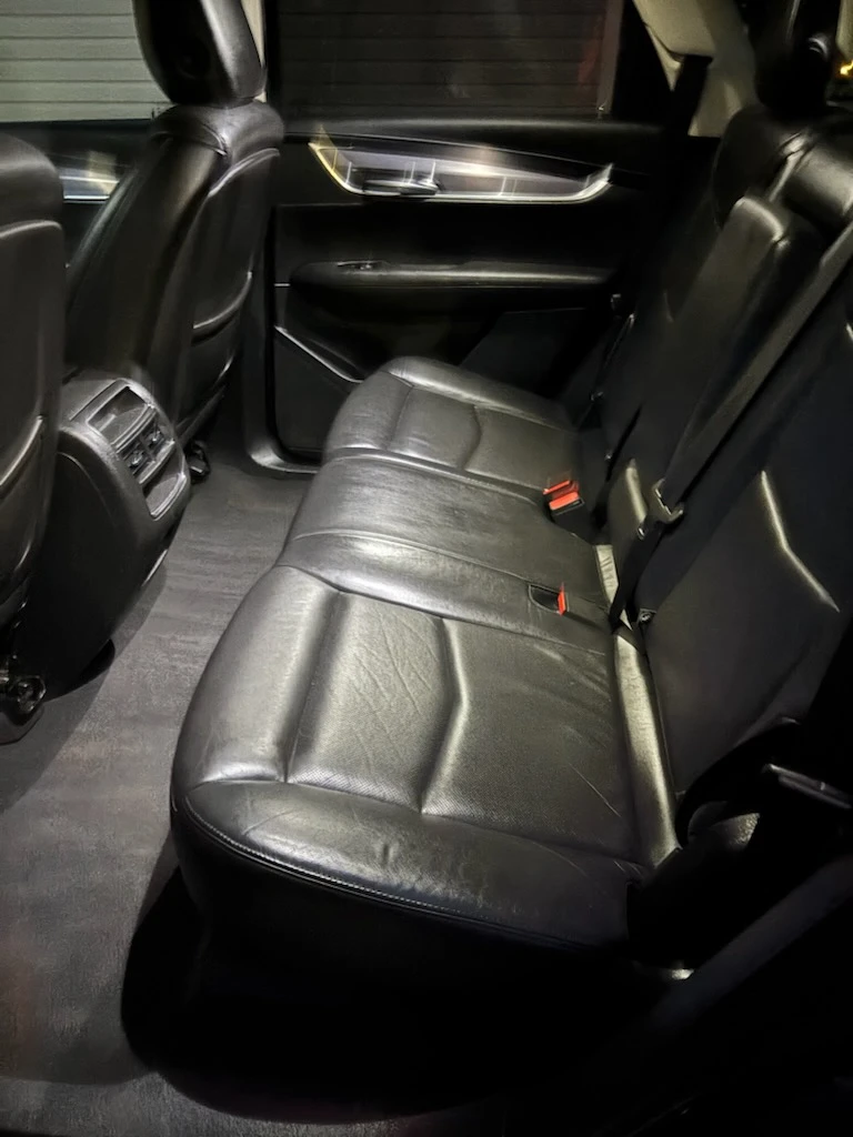 Clean black leather rear seats and vacuumed carpet in a Cadillac SUV after an interior detail