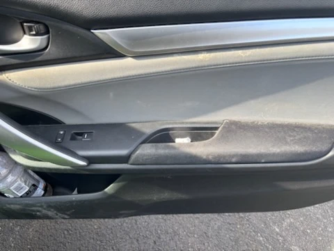 Close up of a soiled vehicle door panel and window switches before detailing