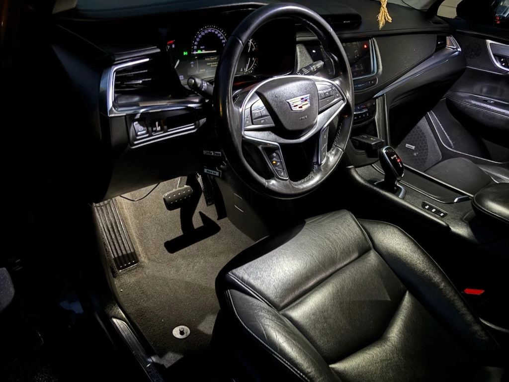 Clean Cadillac XT5 dashboard, steering wheel and black leather seats after an interior detail